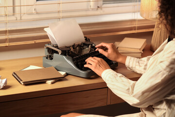 Female author using typewriter at table at home