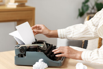Female author using typewriter at table at home