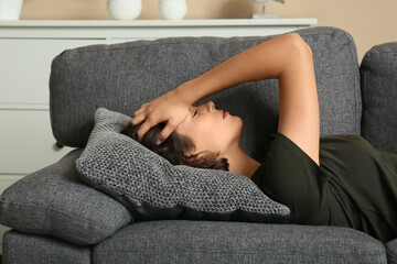 Obraz premium Depressed young woman lying on sofa in living room