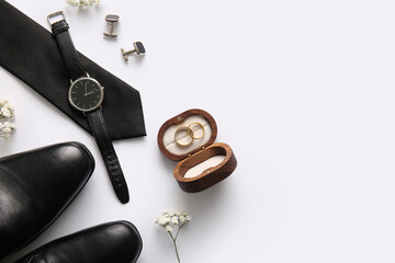 Box with wedding rings, shoes, tie, cufflinks and wrist watch on white background. Top view
