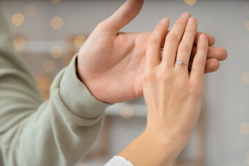 Engaged young couple holding hands at home, closeup