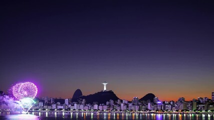 A wide-angle video captures a vibrant city skyline at dusk, with fireworks illuminating the sky above a tranquil waterfront, creating a festive atmosphere. - Powered by Adobe