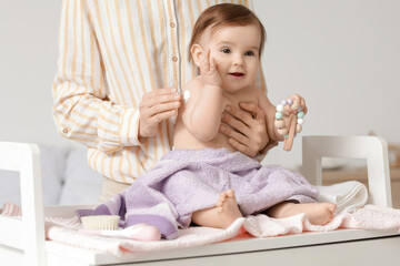 Fototapeta premium Mother applying cream on her little baby's hand on changing table in bedroom. Closeup