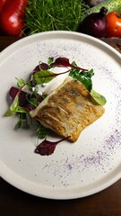 Fried pike perch fillet with herbs and vegetables on a wooden cutting board
