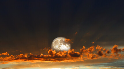 Aufgehender Vollmond im orangfarbenen Sonnenuntergang mit Wolken