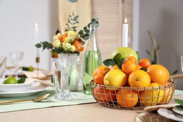 Table setting with basket of citrus fruits in room. Closeup