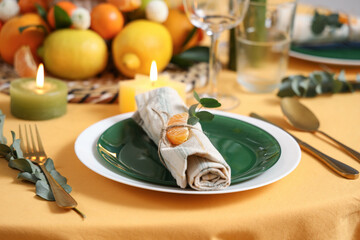 Beautiful table setting with citrus fruits and burning candles in room. Closeup