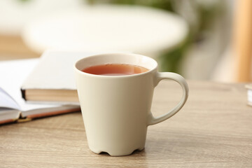 Cup of hot tea on wooden table on blurred background. Closeup