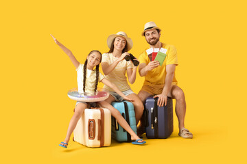 Naklejka premium Family of tourists sitting on suitcases with travel accessories, passports and tickets on yellow background
