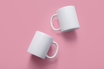 White stylish ceramic mugs on pink background. Top view