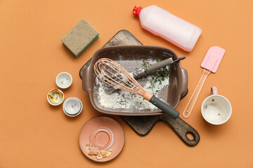 Dirty dishes, detergent and sponge on orange background. Top view