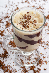 Creamy frothy cold coffee drink with cacao nibs on top and chocolate
