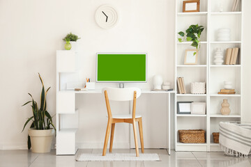 Modern workplace with computer and shelving unit near white wall in room