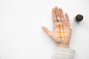 Female hand with iodine mesh, cotton swab and bottle of iodine on white background. Top view