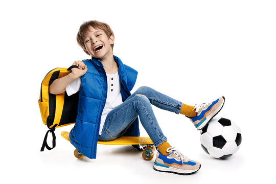 Cute laughing blonde boy sitting on yellow skateboard on white background. Back to School.