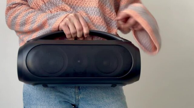 beautiful woman holding portable music speaker and pressing buttons