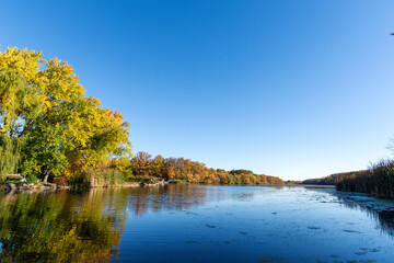 The late October sun highlights the fall foliage as a bench overlooks a pond in Wisconsin.