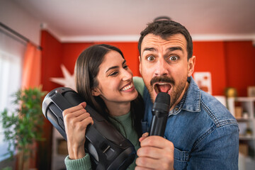 young excited couple dance and sing karaoke on microphone at home