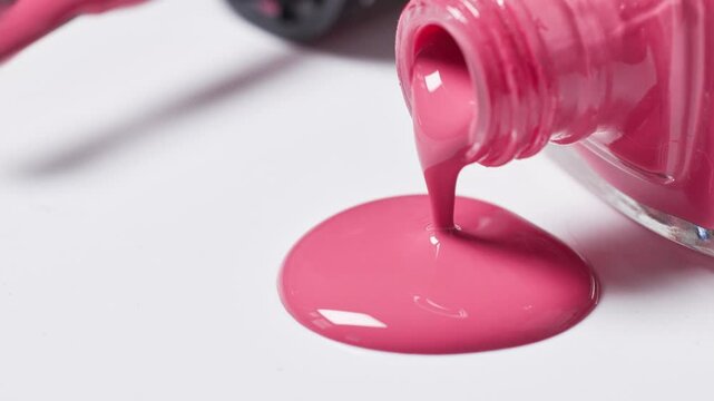 charming pink nail polish slowly dripping from a bottle onto a white surface, cosmetic close-up macro zoom in