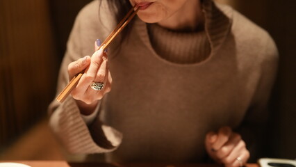 Obraz premium 女性が箸を持ち食事をする