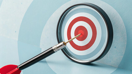 Business goal strategy and target concept. Magnifying glass focusing on red target with arrow dart symbolizes goal setting, precision, business strategy, success, achieving objectives, target market