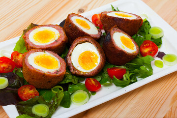Meat stuffed eggs served with cherry tomatoes and greens - Scottish food