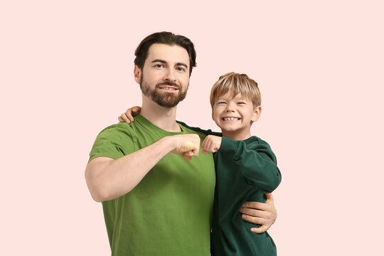 Dad and little son making fist bump gesture on pink background. Father's day - Powered by Adobe