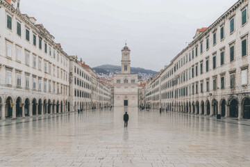 A man stands in the middle of a large, empty plaza