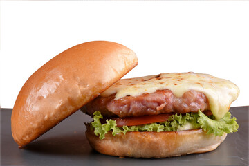beef burger with sandwich bun salad onion and cheese fast food isolated on wooden table