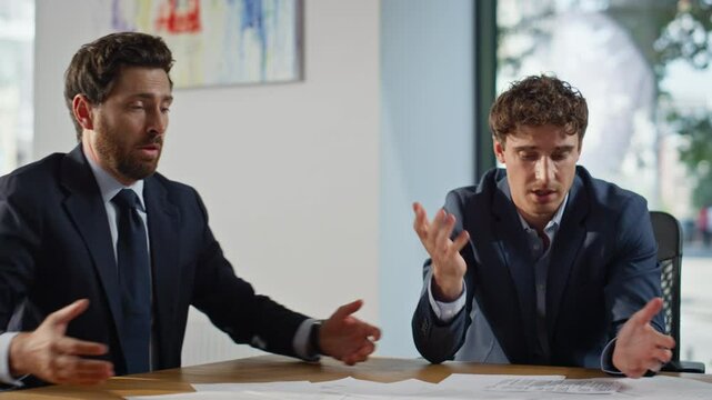 Confused businessmen having problem examining reports mistake at table closeup