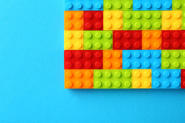 Constructor toy. Many colorful building blocks on light blue background, top view. Space for text