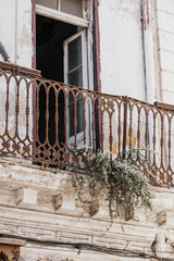 A weathered balcony, adorned with an ornate, rusty iron railing.