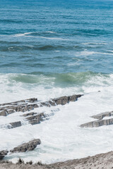 Rocky shoreline with powerful waves crashing against the jagged rocks.  