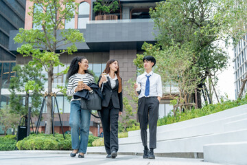 Fototapeta premium Three young adults walking together in modern urban setting, enjoying drinks and engaging in conversation, showcasing vibrant city atmosphere
