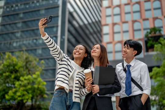 Young professionals taking selfie outdoors in modern urban setting, showcasing joy and camaraderie. scene captures moment of friendship and teamwork