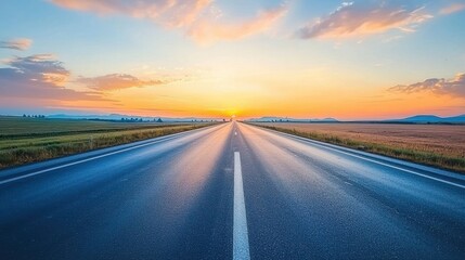 Naklejka premium A straight highway disappearing into the horizon, framed by a vibrant sunset sky.