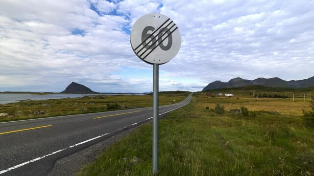 Time lapse from Lofoten of road through a beautiful green landscape with moving clouds above and a sign ending a 60 km speed limit
