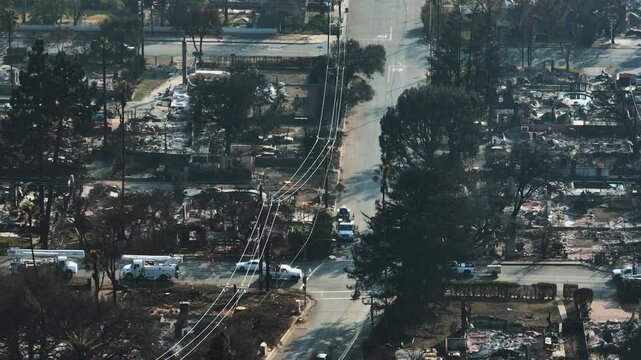 Aerial view tracking cars driving in middle of fire devastation in Altadena, LA
