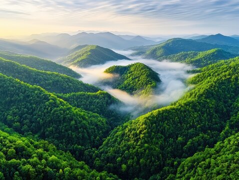 Breathtaking mountain range surrounded by a misty fog with dramatic clouds hovering above, creating a majestic and mysterious landscape