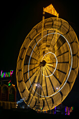 Intentional camera movement, slow shutter , blur image of giant Ferris wheel illuminated and spinning at night in a funfair.