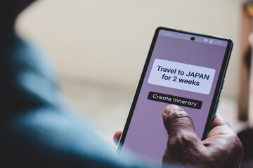 Man using mobile applications on his phone to make travel itinerary for his upcoming Japan trip. Holiday planning using artificial intelligence concept, selective focus.