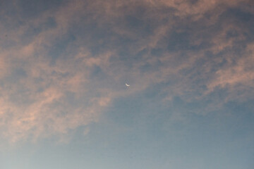Crescent moon in sunset sky, blue and pink