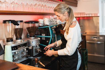 Young female barista making fresh coffee with a high-end coffee machine
