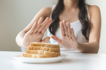 Gluten allergy, asian young woman hand push out, refusing to eat white bread slice on plate in...