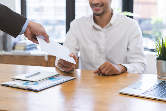 Good job Asian manager business man giving financial reward in an envelope, business letter extra salary to company employee, male worker office hand received premium bonus, getting cheque from boss.