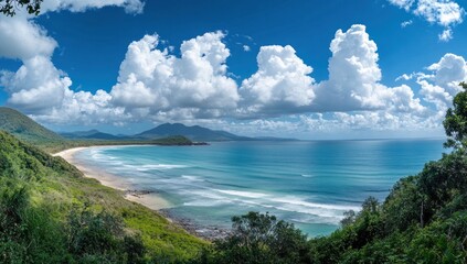 Fototapeta premium Panoramic view of a tropical beach, lush green hills, and a vast ocean under a vibrant blue sky with fluffy white clouds.