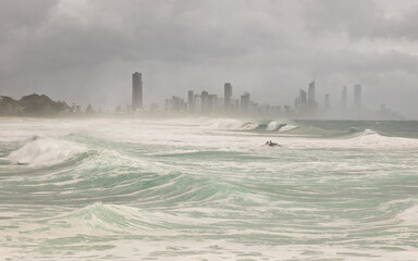 Heavy surf with a personal water craft taking a surfer out to catch a wave, with Surfers Paradise...
