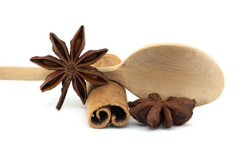 Aromatic star anise and cinnamon stick still life composition with a wooden spoon on white.