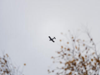 Small ultralight airplane with overhead wing and single propeller flying in sunset sky.