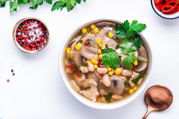 Spicy soup with chicken, mushrooms, corn, white beans, chili and cilantro. White background, top view